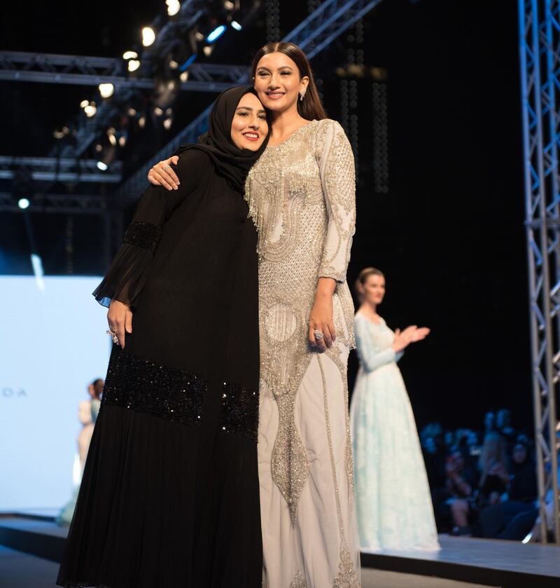 Murcyleen Peerzada on the runway, with a model wearing one of her creations