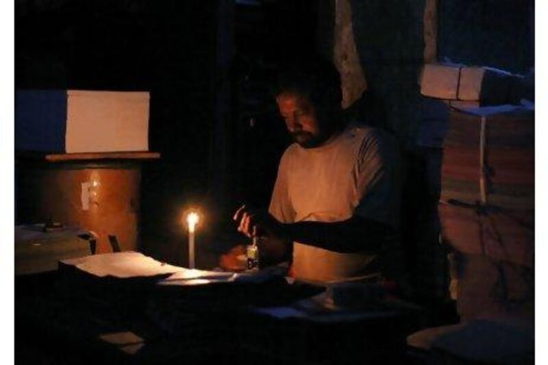 A labourer works by candlelight during a power cut at a printing press shop in Karachi.