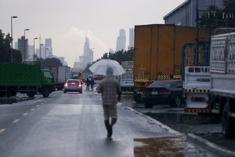 A man uses an umbrella in Al Quoz, a largely industrial area of Dubai. Khushnum Bhandari / The National