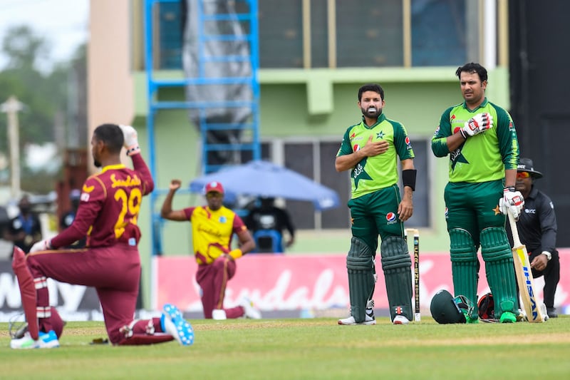 Mohammad Rizwan and Sharjeel Khan of Pakistan hold thier hands across their chests while West Indies players kneel for Black Lives Matter in Providence, Guyana.