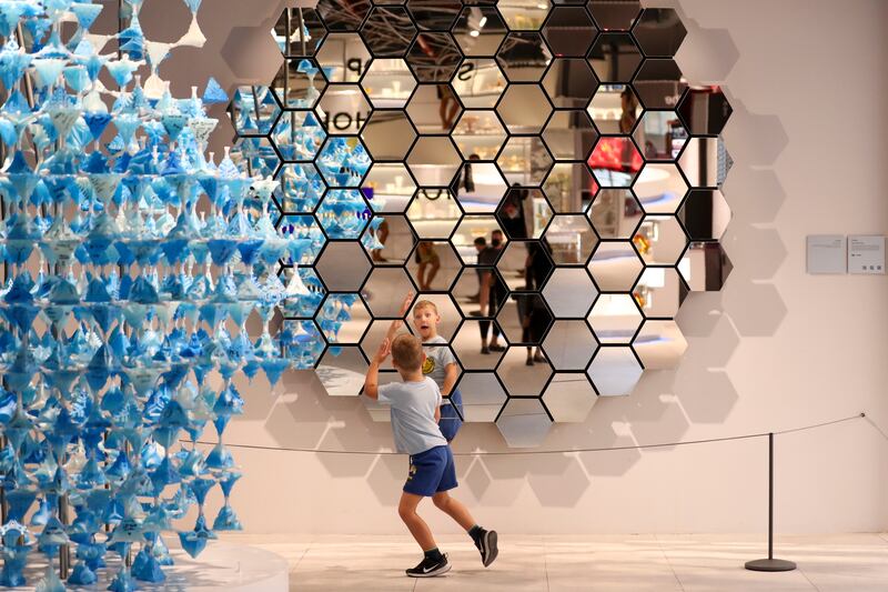 A young visitor stands in front of 'Fluidum', a kinetic statue made up of 85 robotically-controlled mirrors, which can transform the reflection of the spectator, at the Czech Pavilion. Khushnum Bhandari/ The National