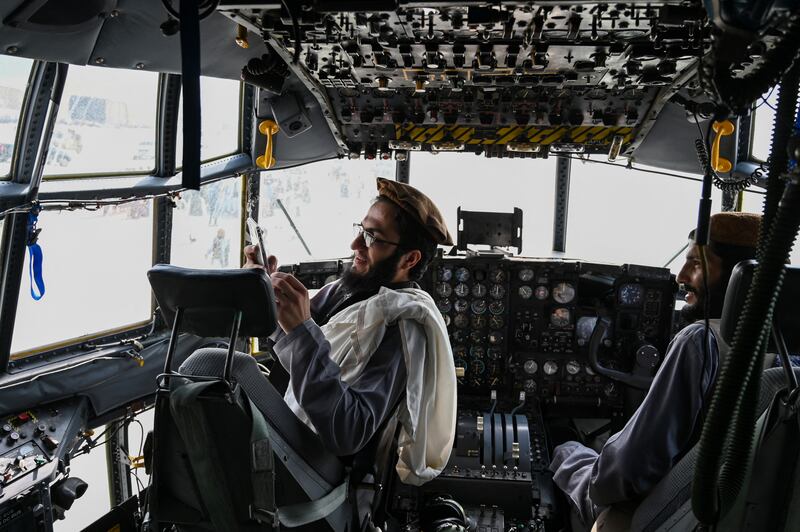 Taliban fighters sit in the cockpit of an Afghan Air Force aircraft at the airport in Kabul on August 31, 2021. AFP