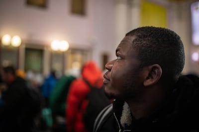 Ojama Akpoga glances up at the departure board in the ticket hall of Lviv railway station. Oliver Marsden for The National