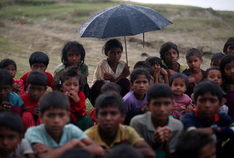 REFILE - CORRECTING DATE Rohingya refugee children sit in a line in the rain as they wait to receive permission from the Bangladeshi army to continue their way after crossing the Bangladesh-Myanmar border, at a port in Teknaf, Bangladesh, October 31, 2017. REUTERS/Hannah McKay