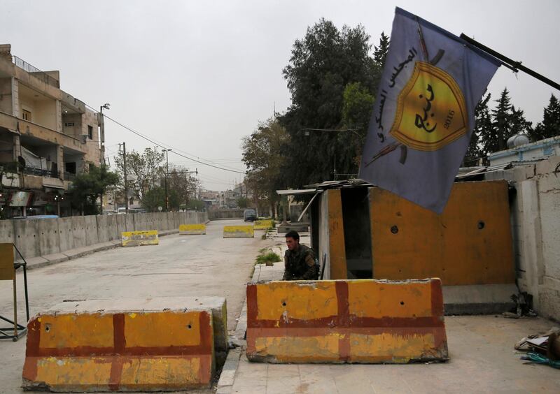 FILE -- In this March 28, 2018 file photo, a Syrian fighter from the Kurdish police force, guards the entrance of the Manbij Military Council, the Kurdish-led, US-backed, militia group that defends Manbij, Syria. Early Tuesday, March 26, 2019, gunmen attacked a checkpoint at one the entrances of Manbij, killing seven fighters, an official with the council said. The Britain-based Syrian Observatory for Human Rights, a war monitor, said sleepers cells of the Islamic State group carried out the attack. (AP Photo/Hussein Malla, File)