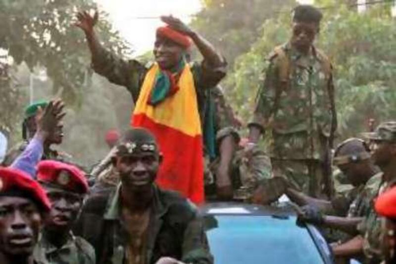 Captain Moussa Dadis Camara, (C) leader of the putschist camp makes a tour of the city, wearing a Guinean flag, on December 24, 2008 in Conakry. Hundreds of soldiers took to the streets of Guinea's capital Conakry, the day after a military junta said it had seized power following the death of President Lansana Conte, an AFP journalist witnessed. Mutinous soldiers behind a coup plot in Guinea accused loyalist troops of seeking "the intervention of foreign mercenaries from neighbouring countries," in a statement read on national radio.   AFP PHOTO / SEYLLOU *** Local Caption ***  969301-01-08.jpg