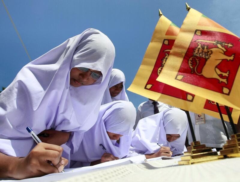 Muslim school girls sign a petition against a U.N. panel's report about Sri Lanka's war crimes, in Colombo April 21, 2011. The report to U.N. Secretary General Ban Ki-moon alleging tens of thousands of civilians were killed and war crimes committed at the end Sri Lanka's war in 2009 drew widespread political reaction this week from the Sri Lankan government. REUTERS/Dinuka Liyanawatte (SRI LANKA - Tags: POLITICS)