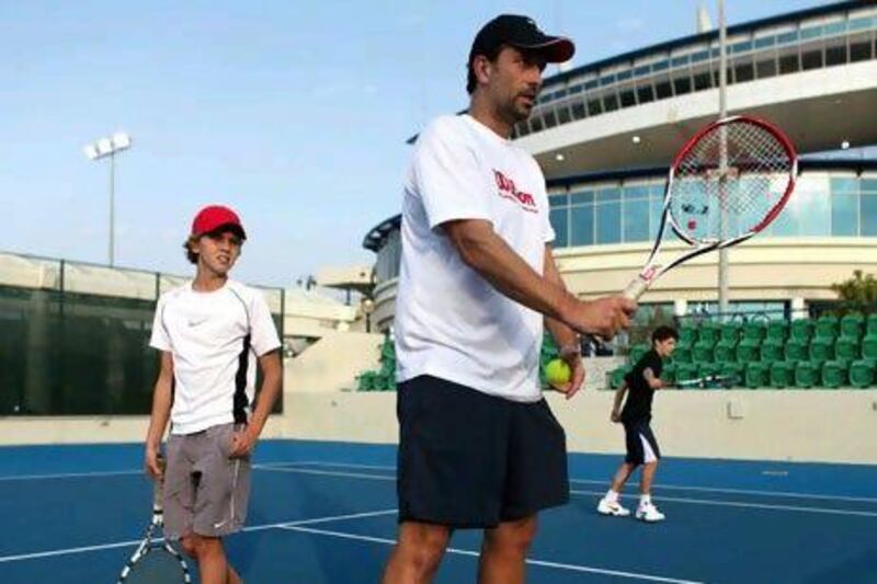 Tennis coach Sigi Meeuws gives a lesson to Daniel Alonso, 12, and Victor Longuet, 14, in Abu Dhabi.