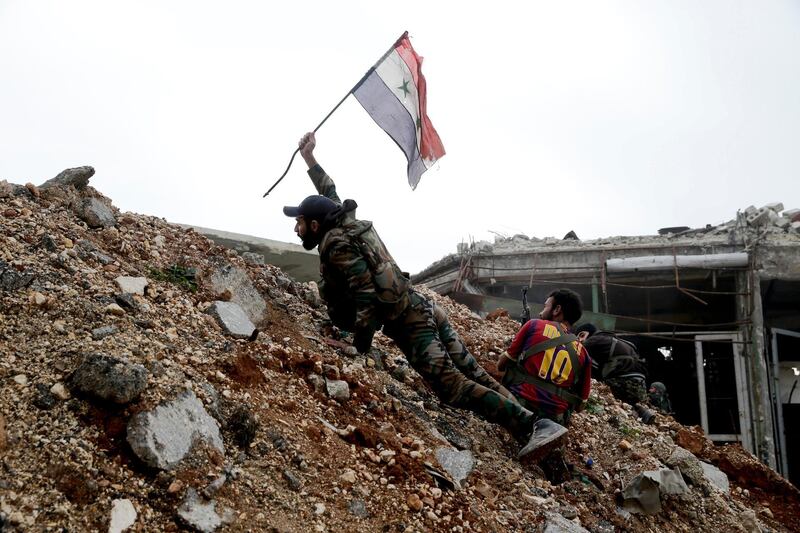 An army soldier places a Syrian national flag during a battle with rebel fighters at the Ramouseh front line, east of Aleppo.