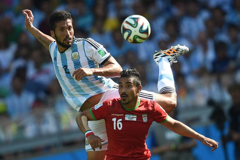 Argentina defender Ezequiel Garay, left, and Iran forward Reza Ghoochannejhad vie for the ball during their match on Saturday at the 2014 World Cup. Pedro Ugarte / AFP