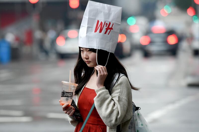 A pedestrian wears a shopping bag as a hat as they walk in heavy rain in Sydney's central business district, New South Wales, Australia.  EPA