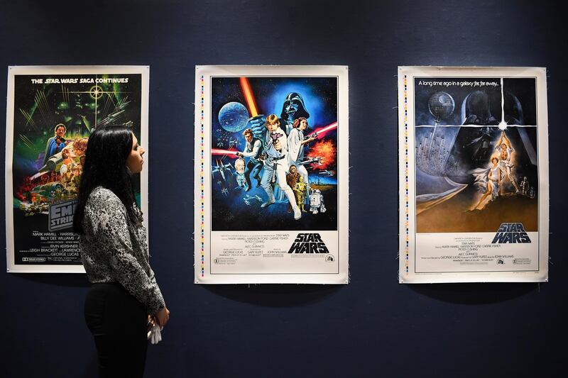 A Sotheby's employee looks at the original Star Wars posters as part of the auction in London. Sotheby's will now host its second sale dedicated to 'Star Wars' collectibles, titled 'Star Wars Online'. AP Photo