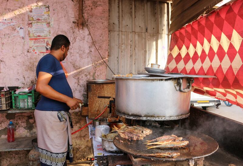A street food vendor fries fish at his stall in the southern Yemeni city of Lahj.