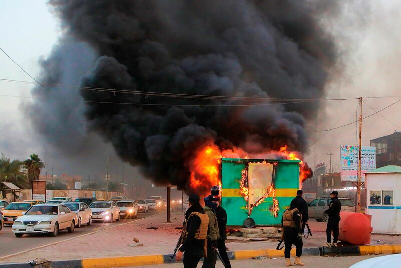 Security forces gather near a burning police checkpoint in Basra, southern Iraq. AP