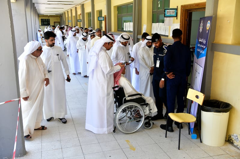 Voters queue at a school in Al Riqqa district as they wait to cast their ballots in the National Assembly polls. AP