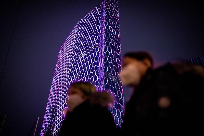 People wearing protective facemasks walk past the Intercontinental Hotel in Beijing. AFP