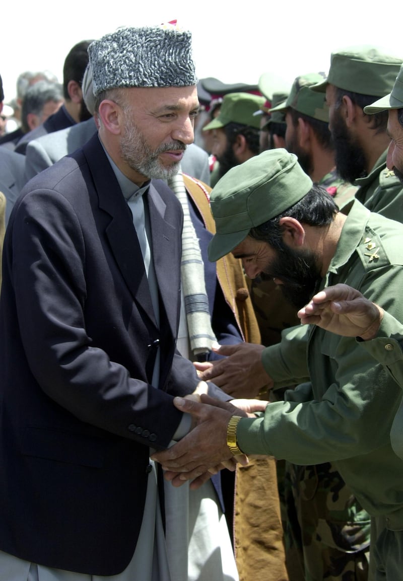 404929 03: Interim Afghan leader Hamid Karzai (L) is greeted by a group of Afghan military officers on his arrival to Kandahar airbase May 04, 2002 in Southern Afghanistan. The visit by Karzai to the city, his first since assuming power, is significant because of the city's history as a former Taliban stronghold. (Photo by Scott Nelson/Getty Images)