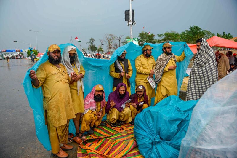 JUI supporters look on as they gather under the rain. AFP