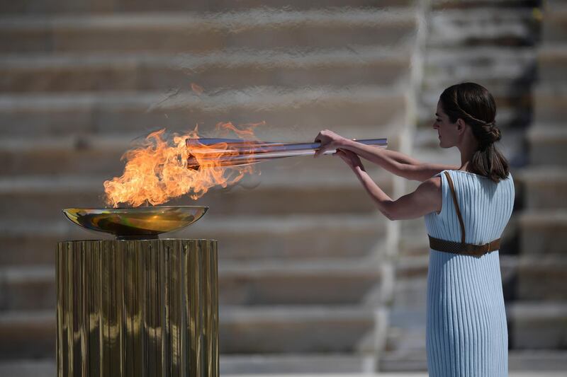 Greek actress Xanthi Georgiou, dressed as an ancient Greek high priestess, lights the Olympic torch during the flame handover ceremony in Athens for the 2020 Tokyo Olympics. AP