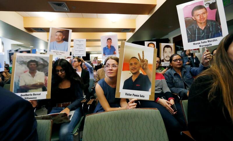 Bea Abbott, center, joins other attendees in holding up placards bearing the photographs of people who went missing while trying to cross the border from Mexico into the United States during a hearing held by the Inter-American Commission on Human Rights Friday, Oct. 5, 2018, at the University of Colorado in Boulder, Colo. Human rights and advocacy groups from Latin America and U.S border states are pressing for access to an FBI DNA database to help identify the remains of hundreds of migrants reported missing along the U.S.-Mexico border. (AP Photo/David Zalubowski)