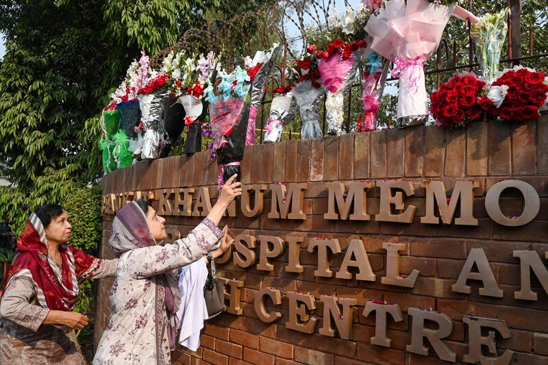 A supporter of Pakistan's former prime minister Imran Khan, places flowers outside the hospital in Lahore where Mr Khan is recovering after an assassination attempt that left him with a gunshot wound to the leg. AFP