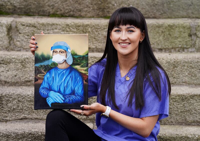 Trainee nurse Chloe Slevin, with her painting 'Corona Lisa'. The interpretation of Leonardo da Vinci's masterpiece in PPE clothing will be auctioned for charity. PA