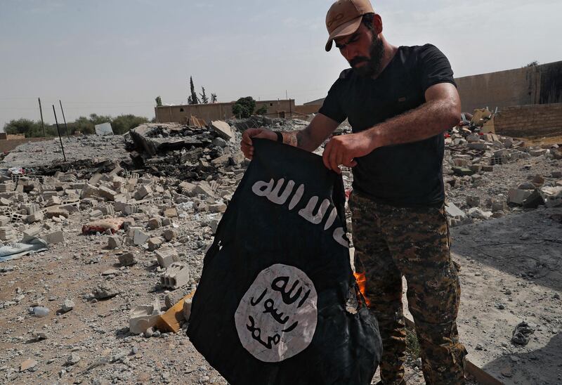 FILE - In this July 17, 2017, file photo, a fighter of the Christian Syriac militia that battles Islamic State group militants under the banner of the U.S.-backed Syrian Democratic Forces, burns an IS flag on the front line on the western side of Raqqa, northeast Syria. The IS erupted from the chaos of Syria and Iraq's conflicts and swiftly did what no Islamic militant group had done before, conquering a giant stretch of territory and declaring itself a "caliphate." U.S. officials said late Saturday, Oct. 26, 2019 that their shadowy leader Abu Bakr al-Baghdadi was the target of an American raid in Syria and may have died in an explosion. (AP Photo/Hussein Malla, File)