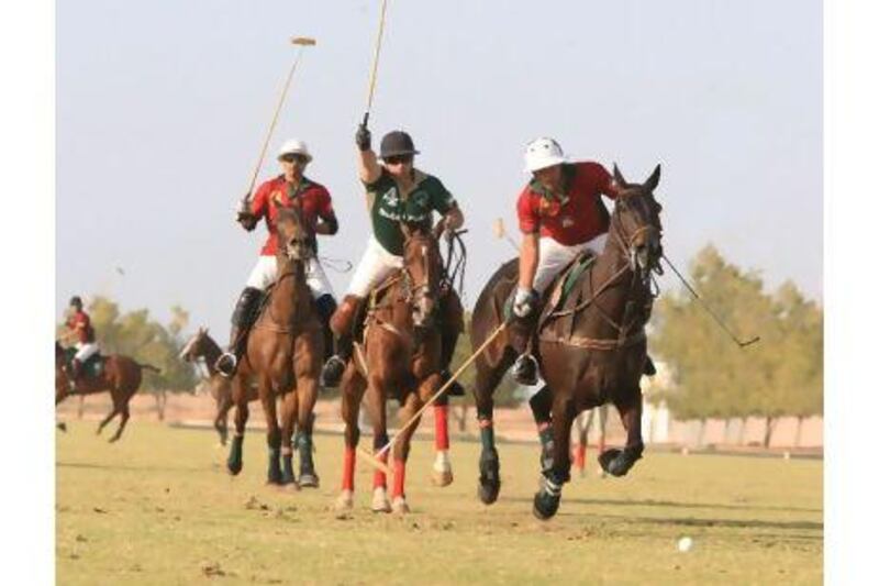 A Ghantoot rider, in red, gallops with a Dubai Polo member, in green, closely in pursuit.