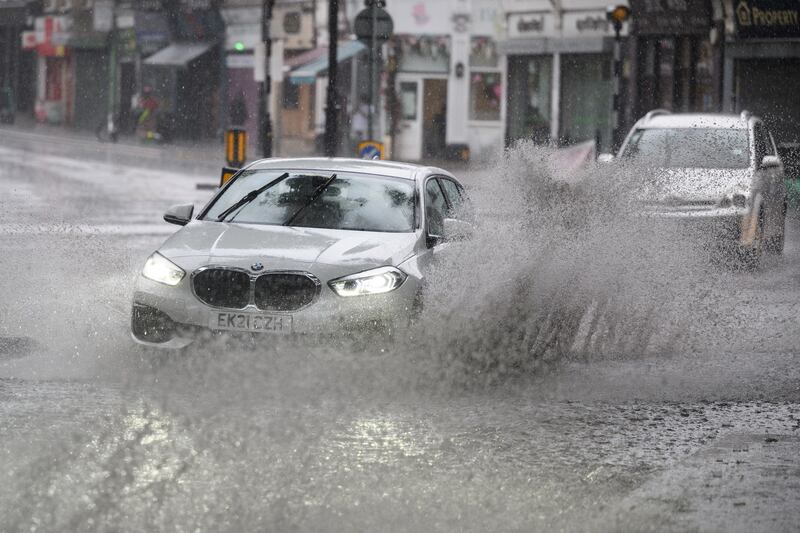 A car sends floodwater spraying in its wake in London. The rain eased later in the week. Getty 
