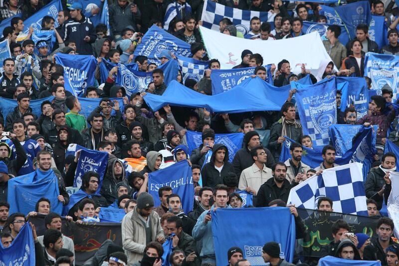 FILE  - In this Dec. 9, 2011 file photo, supporters of Iranian soccer team Esteghlal, hold flags of their favorite team, at the Azadi (Freedom) stadium, in Tehran, Iran. Sahar Khodayari, an Iranian female soccer fan died after setting herself on fire outside a court after learning she may have to serve a six-month sentence for trying to enter a soccer stadium where women are banned, a semi-official news agency reported Tuesday, Sept. 10, 2019. The 30-year-old was known as the "Blue Girl" on social media for the colors of her favorite Iranian soccer team, Esteghlal. (AP Photo/Vahid Salemi, File)