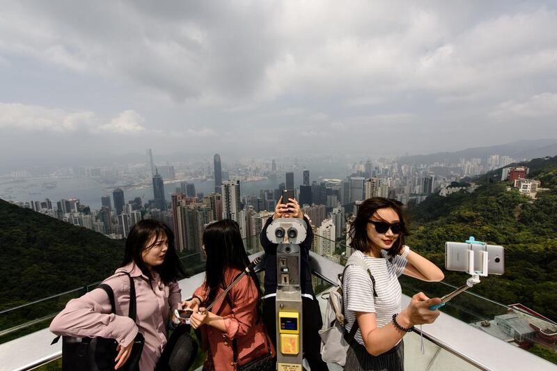 Tourists take selfies during a visit to the viewing deck of Victoria Peak in Hong Kong. Anthony Wallace / AFP