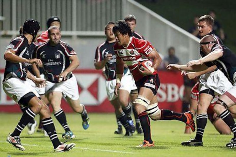 Japan's Takashi Kikutani, centre, runs with the ball past UAE players during their Asian Five Nations (A5N) rugby match last week. The lop-sided 93-3 loss for the UAE is a reminder the Emirtais need some assistance before they go from amateur to professional and find success at the international level. Karim Shahib / AFP