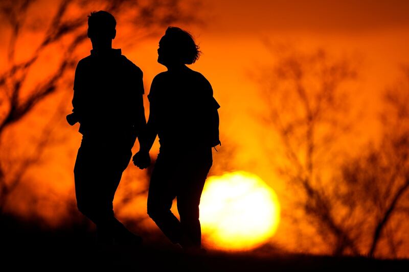 A couple walk through a park at sunset, in Kansas City, US. AP Photo