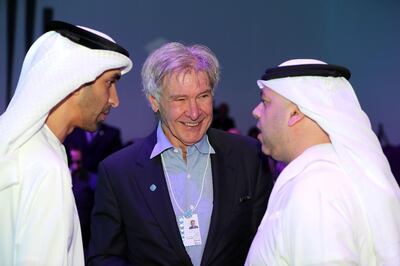Harrison Ford speaks to the Emirati environment minister Dr Thani Al Zeyoudi, left, and another official at the summit on Monday. Chris Whiteoak / The National