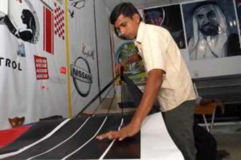 United Arab Emirates - Abu Dhabi - July 1 - 2008: A technician prepares an automotive decorative design at one of the 'car sticker' shops on Salam street. Manuel Salazar/The National

REF rv04saloon 04/07/08 *** Local Caption ***  MS-Terminator-31.jpg
