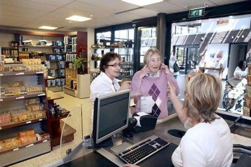 Mrs. Antje Roijter (right) and Petra van Eijk talk with cashier Trudy Vernooy at the store at the Hogewey residential complex.