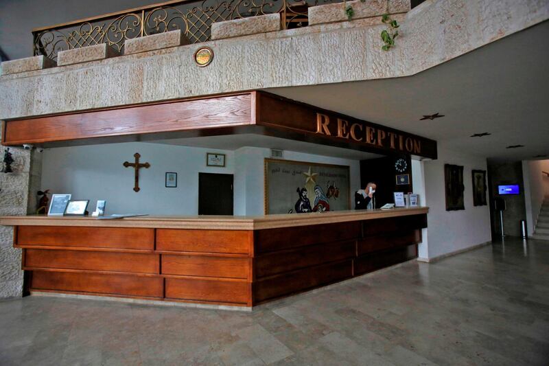 An employee stands at the reception desk of the empty entrance hall of a hotel in the West Bank city of Bethlehem. AFP
