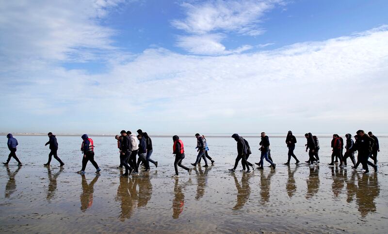 A group of people thought to be migrants walk up the beach after being brought in to Dungeness in May. AP