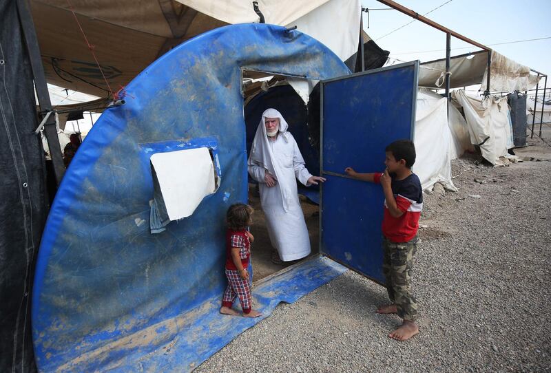 Displaced Iraqis stand at the entrance of a tent in a camp for internally displaced people near al-Khalidiyeh in Iraq's western Anbar province. While the election campaign is in full swing elsewhere in Iraq, the country's displaced camps barely register on the radars of those running for office, despite housing hundreds of thousands of people. Ahmad Al Rubaye / AFP