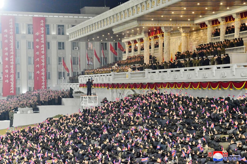 People wave the national flags as North Korean leader Kim Jong-un, centre top, attends a military parade, at Kim Il-sung Square. KCNA / AP