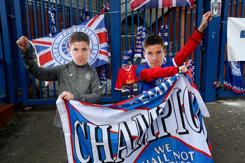 Rangers fans wearing Steven Gerrard masks hold up a banner outside the Ibrox Stadium.