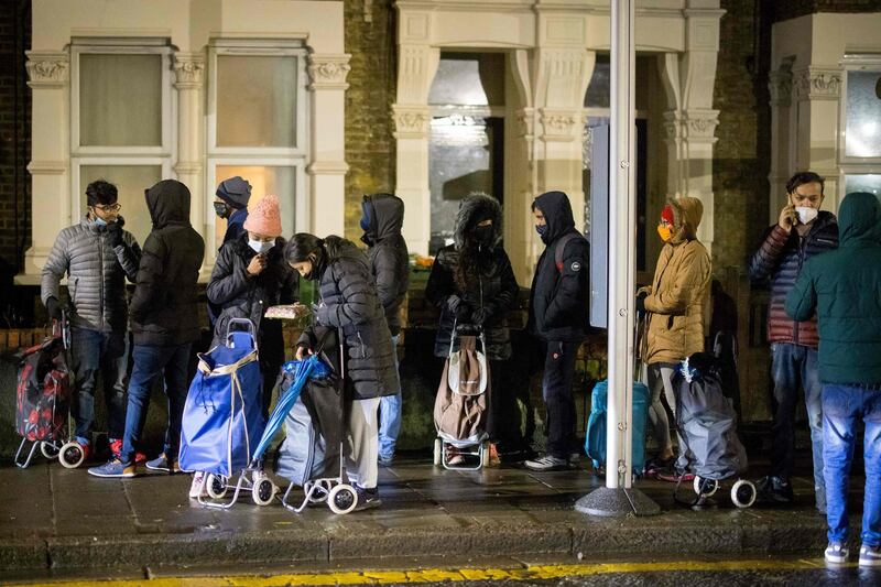 International students queue to collect food packages at the Newham Community Project food bank. AFP