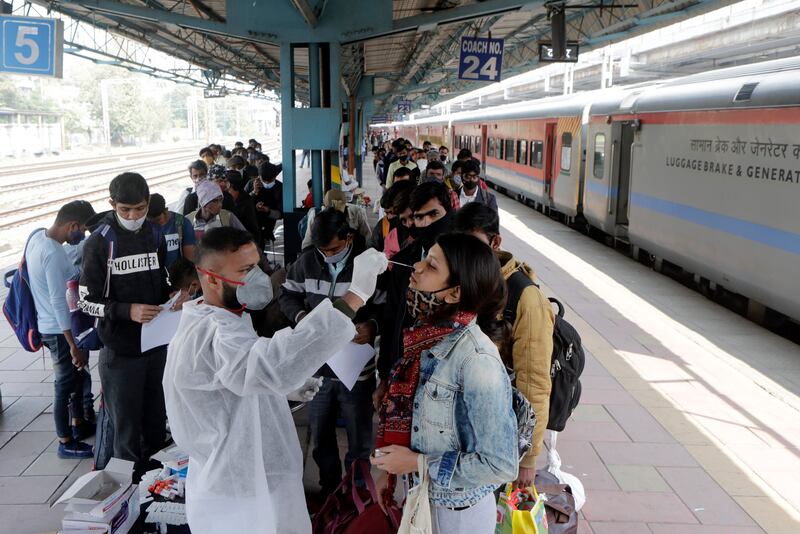 A health worker collects a swab sample from a traveller at a railway station to test for the coronavirus before allowing her to enter Mumbai, India. AP