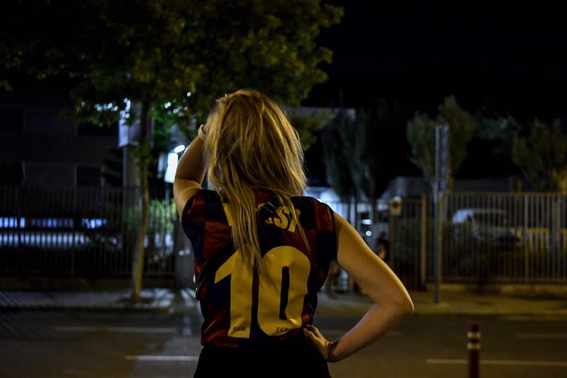 A fan wearing a jersey of Barcelona's Argentinian forward Lionel Messi at the Camp Nou after news that the star player will end his 20-year career with the club.