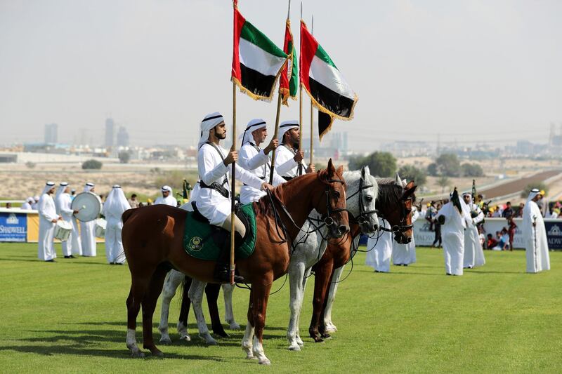Dubai, United Arab Emirates - November 01, 2019: Men on house back carry the UAE flag on the opening meeting at Jebel Ali racecourse. Friday the 1st of November 2019. Jebel Ali racecourse, Dubai. Chris Whiteoak / The National
