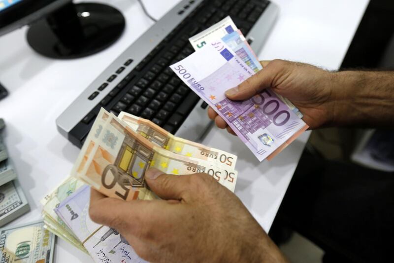 A close up shot shows Iranians trading money at a currency exchange office in a shopping centre in the capital Tehran on April 10, 2018.
Iran took the drastic step of fixing the rate of its currency against the dollar in a bid to arrest a slide that has seen it fall by a third in six months. / AFP PHOTO / ATTA KENARE