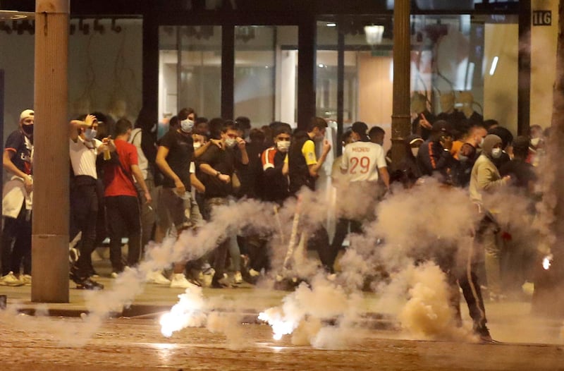 PSG fans try to avoid tear gas on the Champs-Elysees. Reuters