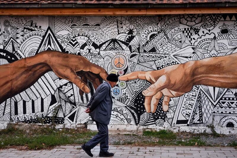 A pedestrian walks past a mural painted on the wall of a house in the town of Ferizaj, Kosovo. AFP