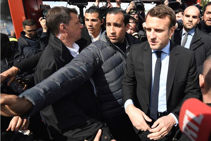 FILE - In this Wednesday April 26, 2017 file photo French centrist presidential election candidate Emmanuel Macron, flanked by his bodyguard, Alexandre Benalla, left, arrives outside the Whirlpool home appliance factory, in Amiens, northern France. Benalla, an aide to President Emmanuel Macron, charged with security, has been seen in a video wearing a police helmet and beating up a student protester in May, reigning criticism on Macron notably due to the light punishment _ a two-week suspension. (Eric Feferberg/Pool via AP, File)
