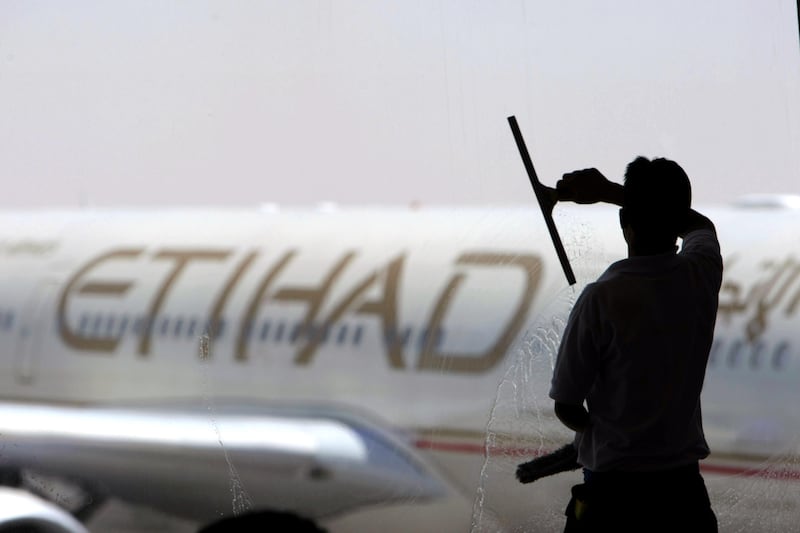 A worker cleans a window with an Etihad plane in the background at Terminal 3 at Abu Dhabi International Airport in 2009. Jaime Puebla / The National
